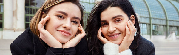 баннер веселой лесбийской пары, смотрящей в камеру возле Пальменхауса в Вене на заднем плане