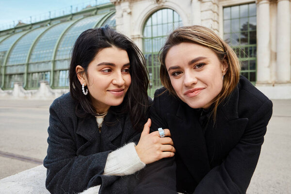 портрет счастливой лесбиянки, смотрящей на свою девушку возле Пальменхауса в Вене на заднем плане