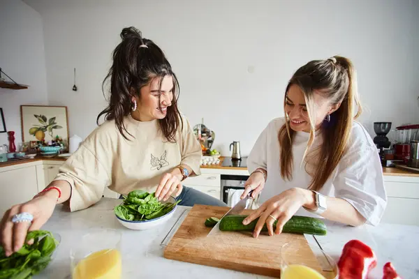 在现代厨房里一起做沙拉时 快乐的年轻女友们笑着说 Lgbtq概念 图库图片