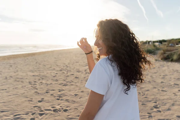 Cheerful young woman in white t-shirt smiling on sandy beach in Spain — Stock Photo