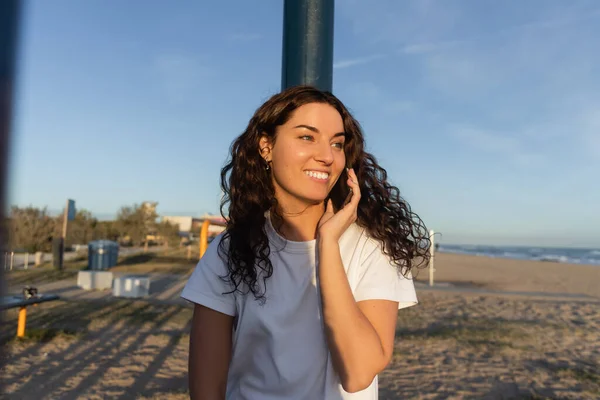 Cheerful young woman talking on smartphone on beach in Barcelona — Stock Photo