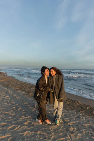 Amigos alegres caminando por la playa de Barcelona al atardecer - foto de stock