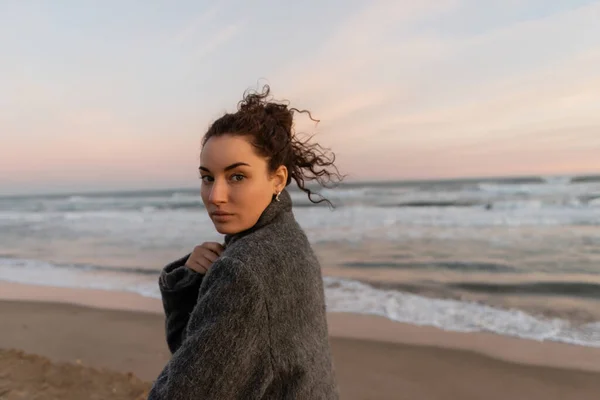 Retrato de mujer rizada mirando a la cámara en la playa en España - foto de stock