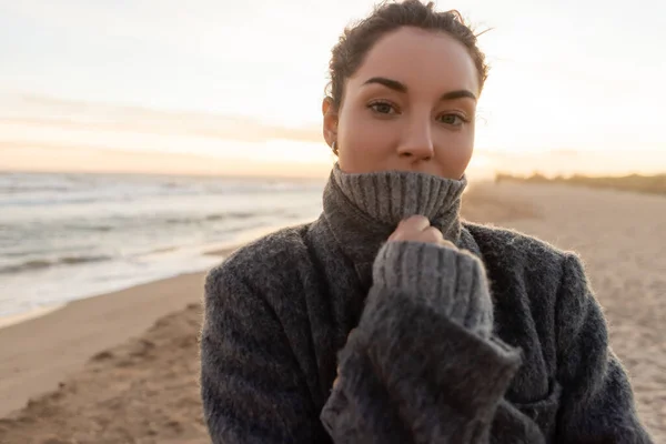 Portrait of woman in coat and sweater looking at camera on beach in Spain — Stock Photo