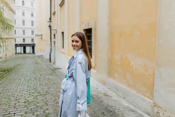 Cheerful woman walking near weathered building with yellow wall on street in Vienna — Stock Photo