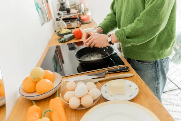 Cropped view of man holding egg near frying pan while cooking breakfast  in morning — Stock Photo