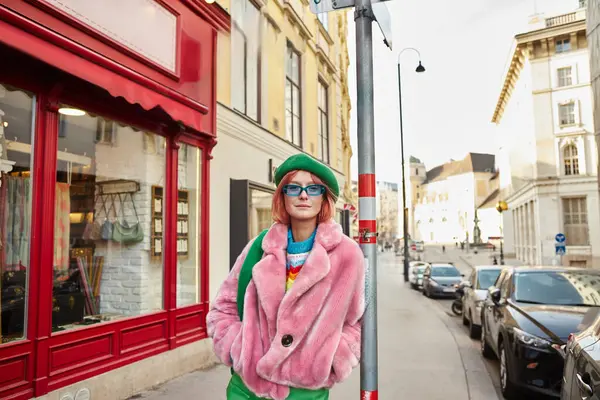 Модная женщина в искусственной меховой куртке и солнцезащитных очках, смотрящая в камеру на городской улице в Вене, Австрия — стоковое фото
