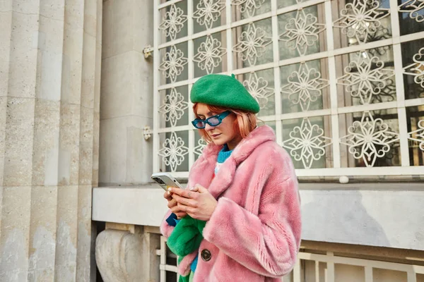 Жінка в сонцезахисних окулярах і модний хутряний піджак, використовуючи смартфон на вулиці у Відні, Австрія — стокове фото