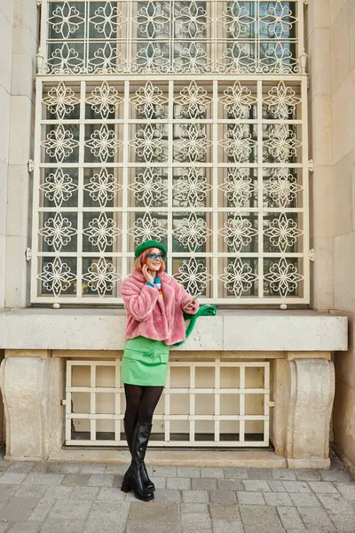 Smiling woman in sunglasses and fashionable casual attire talking on smartphone on street in Vienna — Stock Photo