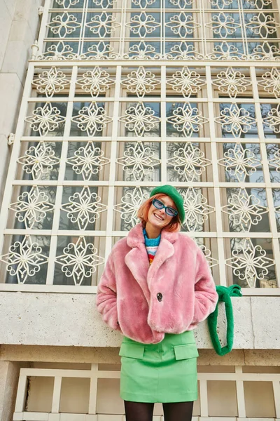 Веселая модная женщина в солнцезащитных очках и искусственной меховой куртке, смотрящая в камеру на улице Вены — стоковое фото