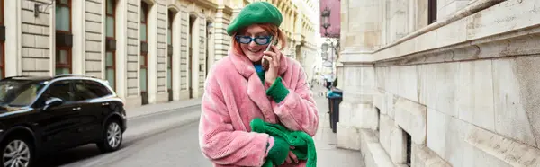 Joyful trendy woman in faux fur jacket and sunglasses talking on smartphone in Vienna, banner — Stock Photo