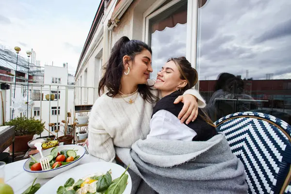 Momento íntimo y feliz de pareja lesbiana abrazándose mientras desayuna en el balcón, concepto lgbt - foto de stock