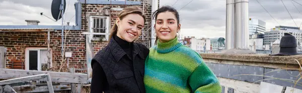 Happy lesbian couple in casual attire standing together of rooftop and looking at camera, banner — Stock Photo