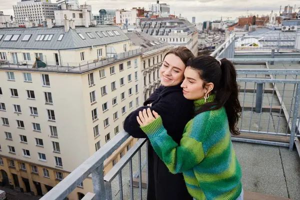 Young lesbian couple in casual attire looking at city on rooftop, a moment of love and connection — Stock Photo