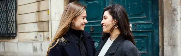 Banner, felice coppia lesbica in cappotti in piedi insieme e guardando l'un l'altro sulla strada urbana — Foto stock