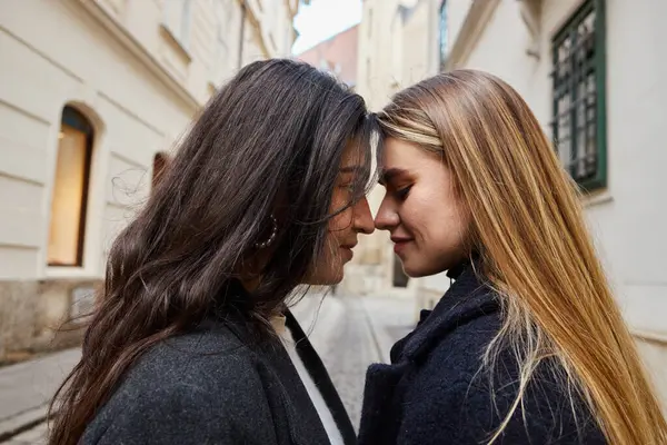 Side view of happy lesbian couple in outerwear standing face to face outdoors, close up — Stock Photo
