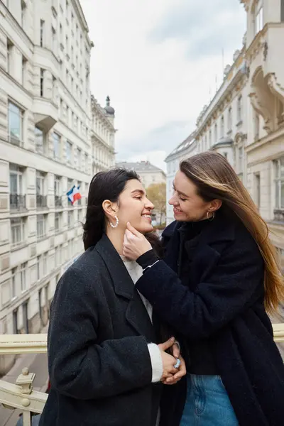 Intimate moment on balcony with city architecture view as backdrop, two lesbian women in love — Stock Photo