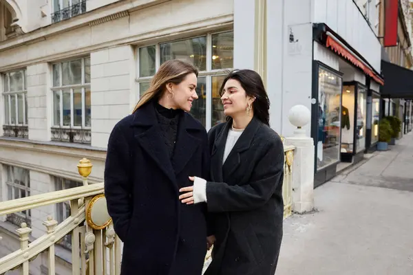 Momento íntimo de mujeres lesbianas alegres enamoradas de pie juntas en la calle en la ciudad europea - foto de stock