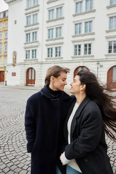 Momento íntimo de alegre pareja lgbt en el amor de pie juntos en la calle en la ciudad europea - foto de stock