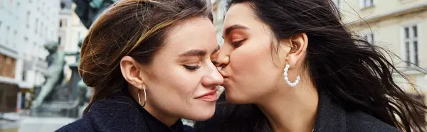 Heureuse lesbienne femme baisers dans joue sa copine par une fontaine statue à Vienne, bannière — Photo de stock