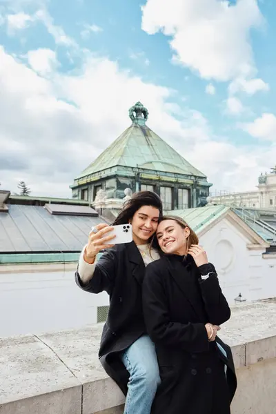 Happy lgbt couple taking selfie on smartphone while standing together on street in Vienna, lesbian — Stock Photo