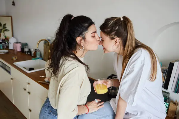 Happy moment of lesbian couple, young woman kissing nose of her girlfriend in kitchen — Stock Photo