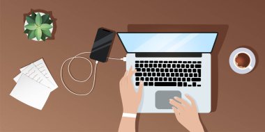 Masaüstü görüntüsü yukarıdan, bir kız dizüstü bilgisayarda çalışıyor, telefonunu şarj ediyor, evraklar yakınlarda duruyor kahve ve sulu.