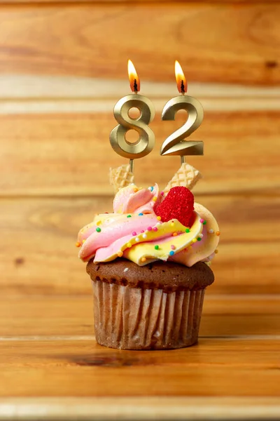 木の背景にゴールデンバースデーキャンドル 番号付きキャンドル付きの誕生日カップケーキ — ストック写真