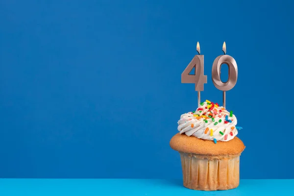 ブルーバックグラウンドの誕生日カップケーキ ピンクの誕生日キャンドル番号 ロイヤリティフリーのストック画像