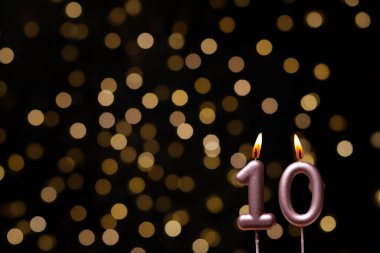 Odaklanamayan ışıklarla arka planı gösteren güzel bir görüntü bir bokeh etkisi yaratarak neşeli ve neşeli bir atmosfer yaratıyor. Bir köşede, iki tane yanan doğum günü mumu biraz sıcaklık ve kutlama katar, özel bir şeyi temsil etmek için mükemmeldir.