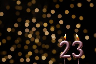 Odaklanamayan ışıklarla arka planı gösteren güzel bir görüntü bir bokeh etkisi yaratarak neşeli ve neşeli bir atmosfer yaratıyor. Bir köşede, iki tane yanan doğum günü mumu biraz sıcaklık ve kutlama katar, özel bir şeyi temsil etmek için mükemmeldir.