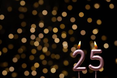 Odaklanamayan ışıklarla arka planı gösteren güzel bir görüntü bir bokeh etkisi yaratarak neşeli ve neşeli bir atmosfer yaratıyor. Bir köşede, iki tane yanan doğum günü mumu biraz sıcaklık ve kutlama katar, özel bir şeyi temsil etmek için mükemmeldir.