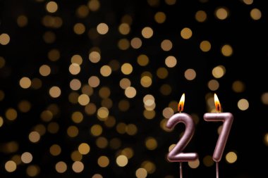 Odaklanamayan ışıklarla arka planı gösteren güzel bir görüntü bir bokeh etkisi yaratarak neşeli ve neşeli bir atmosfer yaratıyor. Bir köşede, iki tane yanan doğum günü mumu biraz sıcaklık ve kutlama katar, özel bir şeyi temsil etmek için mükemmeldir.