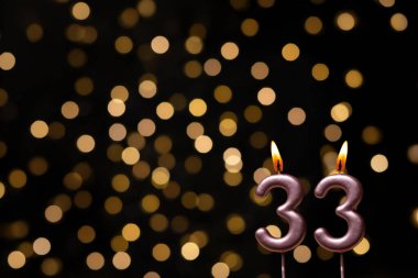 Odaklanamayan ışıklarla arka planı gösteren güzel bir görüntü bir bokeh etkisi yaratarak neşeli ve neşeli bir atmosfer yaratıyor. Bir köşede, iki tane yanan doğum günü mumu biraz sıcaklık ve kutlama katar, özel bir şeyi temsil etmek için mükemmeldir.