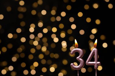 Odaklanamayan ışıklarla arka planı gösteren güzel bir görüntü bir bokeh etkisi yaratarak neşeli ve neşeli bir atmosfer yaratıyor. Bir köşede, iki tane yanan doğum günü mumu biraz sıcaklık ve kutlama katar, özel bir şeyi temsil etmek için mükemmeldir.