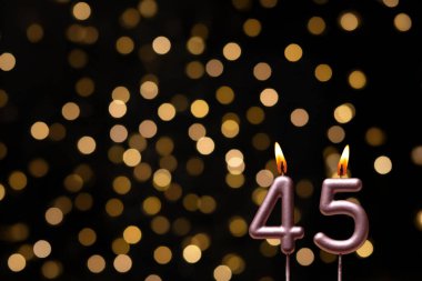 Odaklanamayan ışıklarla arka planı gösteren güzel bir görüntü bir bokeh etkisi yaratarak neşeli ve neşeli bir atmosfer yaratıyor. Bir köşede, iki tane yanan doğum günü mumu biraz sıcaklık ve kutlama katar, özel bir şeyi temsil etmek için mükemmeldir.