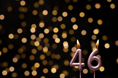 Odaklanamayan ışıklarla arka planı gösteren güzel bir görüntü bir bokeh etkisi yaratarak neşeli ve neşeli bir atmosfer yaratıyor. Bir köşede, iki tane yanan doğum günü mumu biraz sıcaklık ve kutlama katar, özel bir şeyi temsil etmek için mükemmeldir.