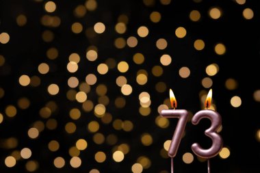 Odaklanamayan ışıklarla arka planı gösteren güzel bir görüntü bir bokeh etkisi yaratarak neşeli ve neşeli bir atmosfer yaratıyor. Bir köşede, iki tane yanan doğum günü mumu biraz sıcaklık ve kutlama katar, özel bir şeyi temsil etmek için mükemmeldir.