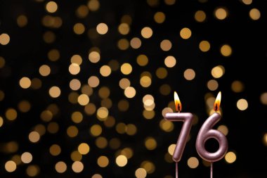 Odaklanamayan ışıklarla arka planı gösteren güzel bir görüntü bir bokeh etkisi yaratarak neşeli ve neşeli bir atmosfer yaratıyor. Bir köşede, iki tane yanan doğum günü mumu biraz sıcaklık ve kutlama katar, özel bir şeyi temsil etmek için mükemmeldir.