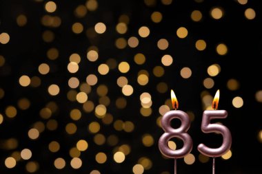 Odaklanamayan ışıklarla arka planı gösteren güzel bir görüntü bir bokeh etkisi yaratarak neşeli ve neşeli bir atmosfer yaratıyor. Bir köşede, iki tane yanan doğum günü mumu biraz sıcaklık ve kutlama katar, özel bir şeyi temsil etmek için mükemmeldir.