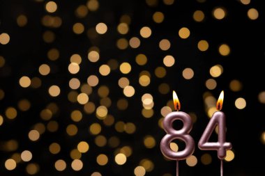 Odaklanamayan ışıklarla arka planı gösteren güzel bir görüntü bir bokeh etkisi yaratarak neşeli ve neşeli bir atmosfer yaratıyor. Bir köşede, iki tane yanan doğum günü mumu biraz sıcaklık ve kutlama katar, özel bir şeyi temsil etmek için mükemmeldir.