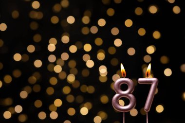 Odaklanamayan ışıklarla arka planı gösteren güzel bir görüntü bir bokeh etkisi yaratarak neşeli ve neşeli bir atmosfer yaratıyor. Bir köşede, iki tane yanan doğum günü mumu biraz sıcaklık ve kutlama katar, özel bir şeyi temsil etmek için mükemmeldir.