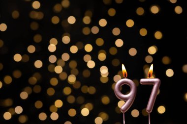 Odaklanamayan ışıklarla arka planı gösteren güzel bir görüntü bir bokeh etkisi yaratarak neşeli ve neşeli bir atmosfer yaratıyor. Bir köşede, iki tane yanan doğum günü mumu biraz sıcaklık ve kutlama katar, özel bir şeyi temsil etmek için mükemmeldir.