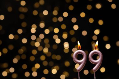 Odaklanamayan ışıklarla arka planı gösteren güzel bir görüntü bir bokeh etkisi yaratarak neşeli ve neşeli bir atmosfer yaratıyor. Bir köşede, iki tane yanan doğum günü mumu biraz sıcaklık ve kutlama katar, özel bir şeyi temsil etmek için mükemmeldir.