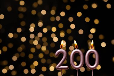 Odaklanamayan ışıklarla arka planı gösteren güzel bir görüntü bir bokeh etkisi yaratarak neşeli ve neşeli bir atmosfer yaratıyor. Bir köşede, iki tane yanan doğum günü mumu biraz sıcaklık ve kutlama katar, özel bir şeyi temsil etmek için mükemmeldir.