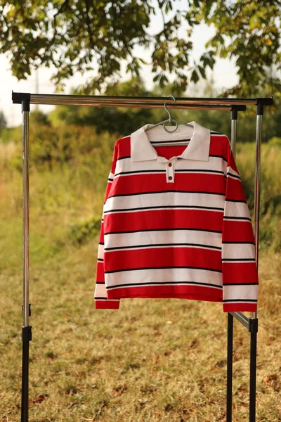 A red and white striped sweater hangs on a hanger.