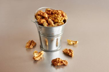 Gri arka planda ceviz dolu küçük metal bir kova. Sağlıklı beslenme kavramı.