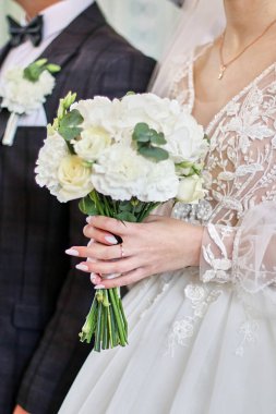 Düğün sırasında gelin, elinde lüks bir buket beyaz gül tutar..