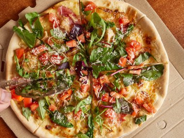 Taze pişmiş pizza bir disk bıçağıyla parçalara ayrılır. Yukarıdan görüntüle.