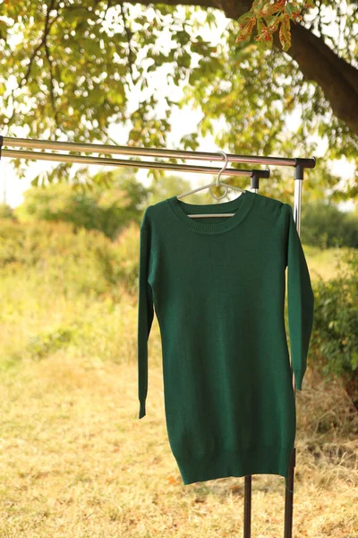 A green woman\'s sweater hangs outside.